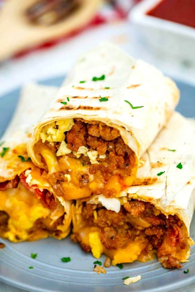 three sausage egg and cheese breakfast burrito halves on a plate