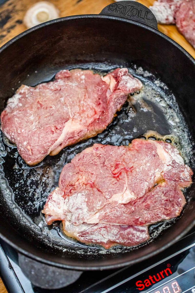 Searing round steaks in a cast iron skillet.