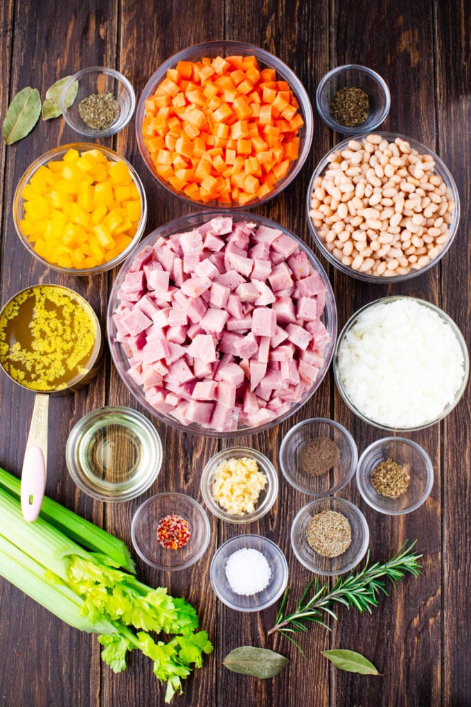 Overhead shot of Instant Pot ham and bean soup ingredients in bowls on a wooden table.