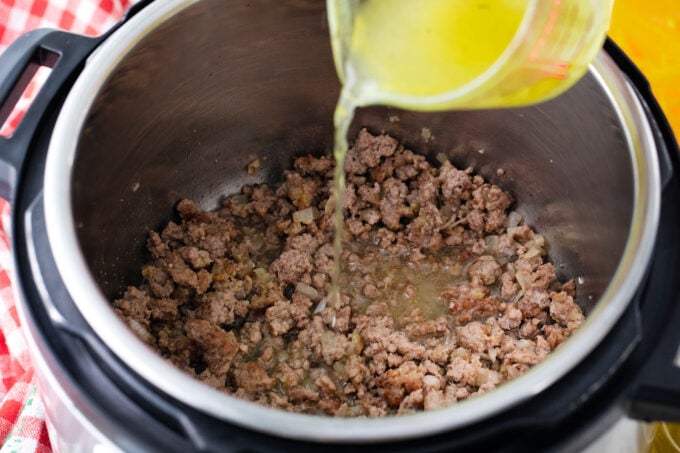 Adding broth to ground beef in the Instant Pot.