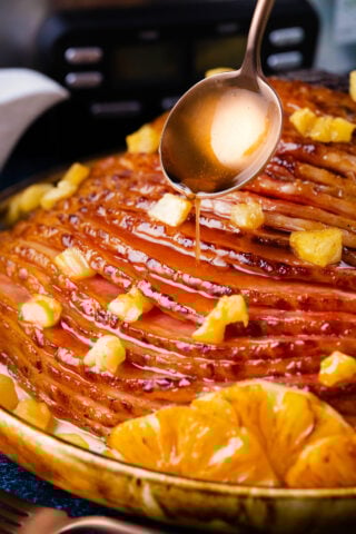Drizzling brown sugar glaze over crockpot pineapple ham.