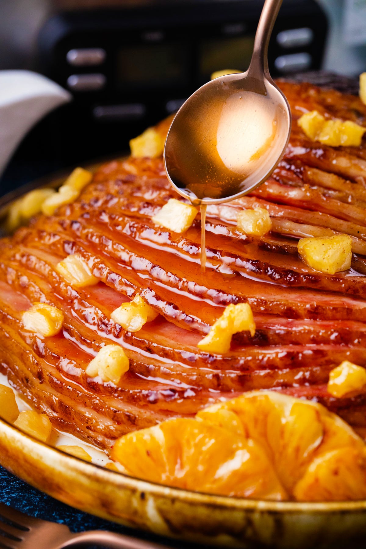 Drizzling brown sugar glaze over crockpot pineapple ham.
