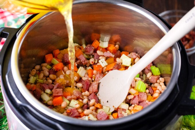 Pouring broth to make Instant Pot ham and bean soup.