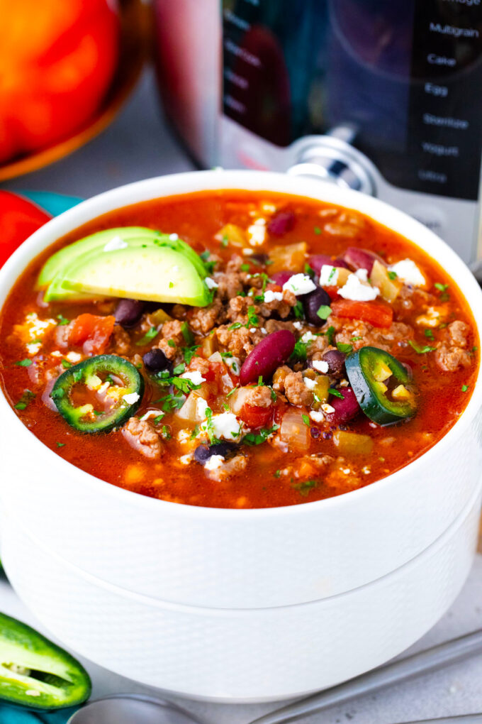 A bowl of Instant Pot taco soup topped with jalapeno slices and avocado.