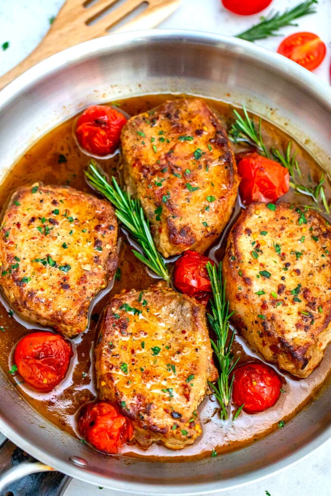 Photo of pan seared pork chops with tomatoes and rosemary.