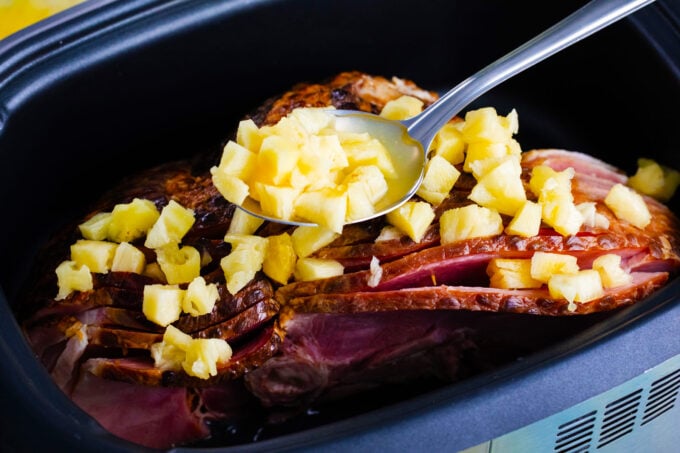 Topping a spiral ham with pineapple pieces.