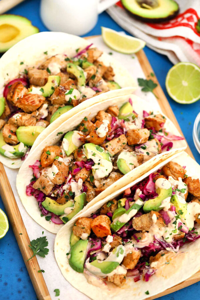 Three homemade chipotle chicken tacos on a serving board