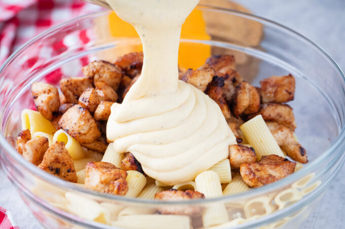 Adding cheesy sauce to chicken and pasta.