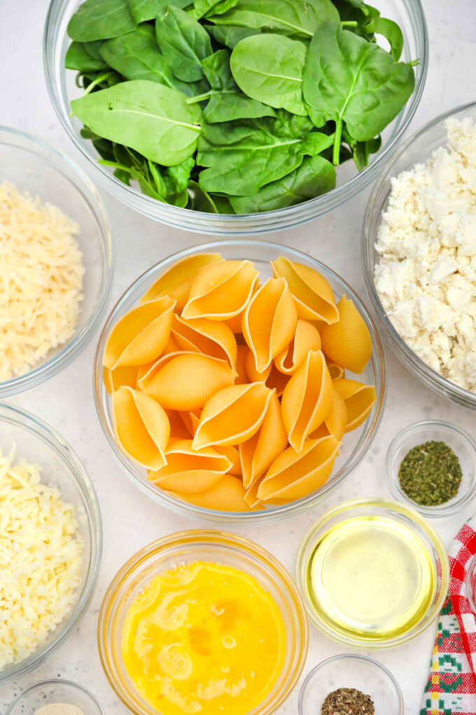 Ricotta stuffed shells ingredients listed in individual gall bowl on a wooden table.