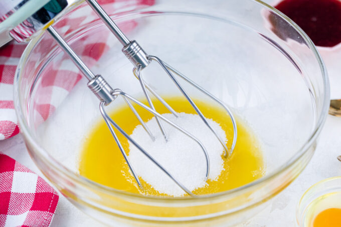 Stirring melted butter and sugar in a bowl.