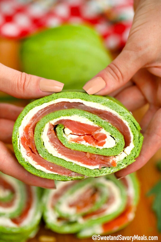 hands holding a slice of Keto arugula salmon roll with cream cheese.