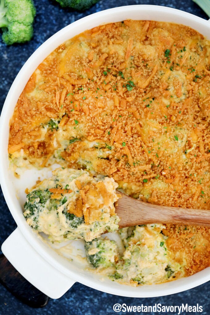 Homemade broccoli casserole with cheese and topped with cracker on a white casserole dish.