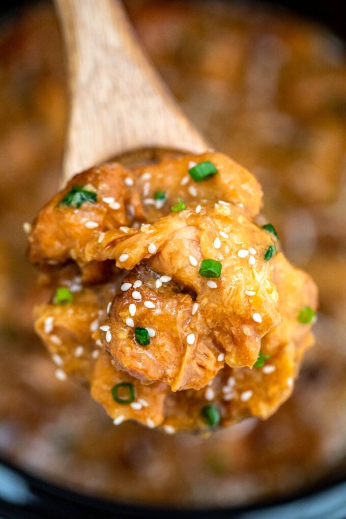 Chinese honey sesame chicken on a wooden spoon