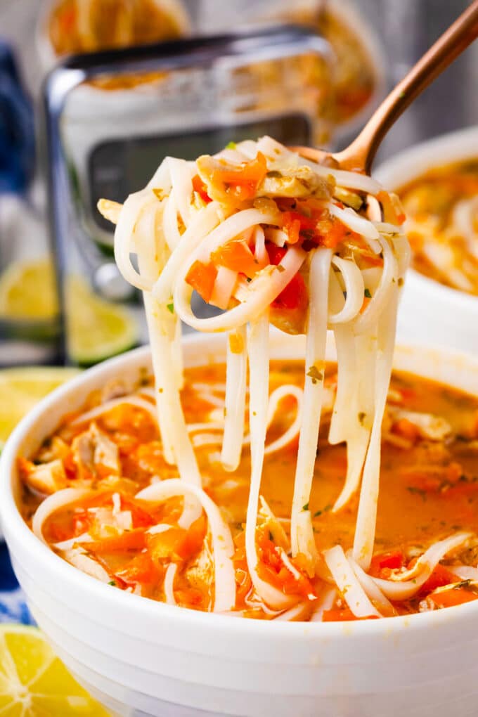 A spoonful of Asian chicken noodle soup with rice noodles.