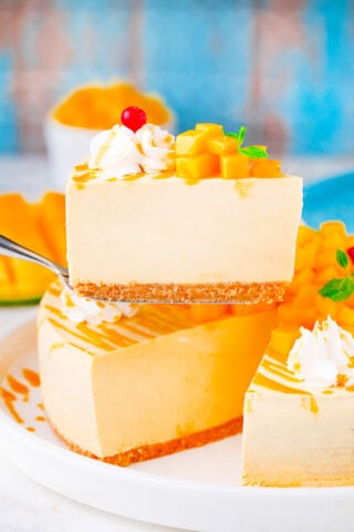 Slice of no bake mango cheesecake topped with fresh mangoes.