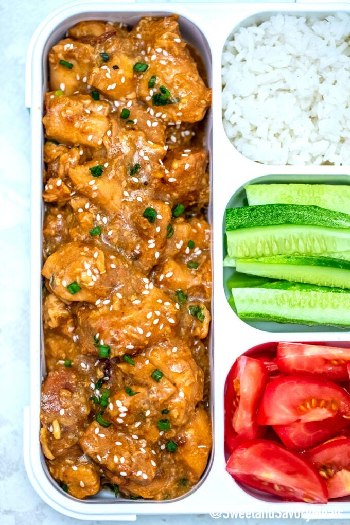 Honey sesame chicken lunch box with white rice, tomatoes, and cucumber
