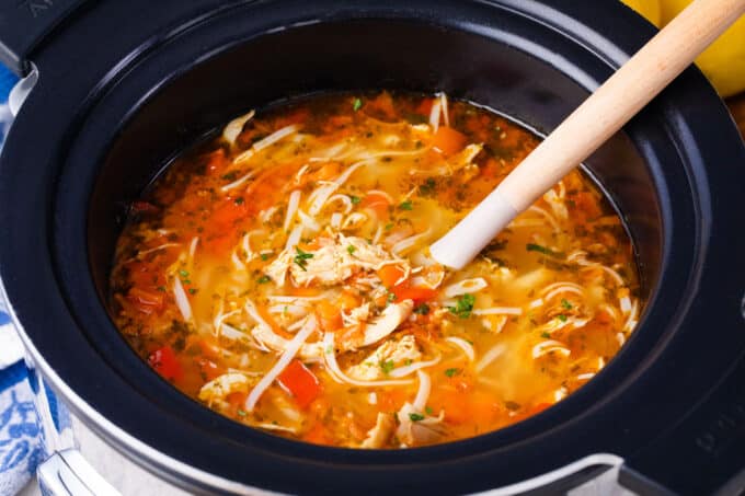 Crockpot Asian chicken noodle soup with veggies and rice noodles.