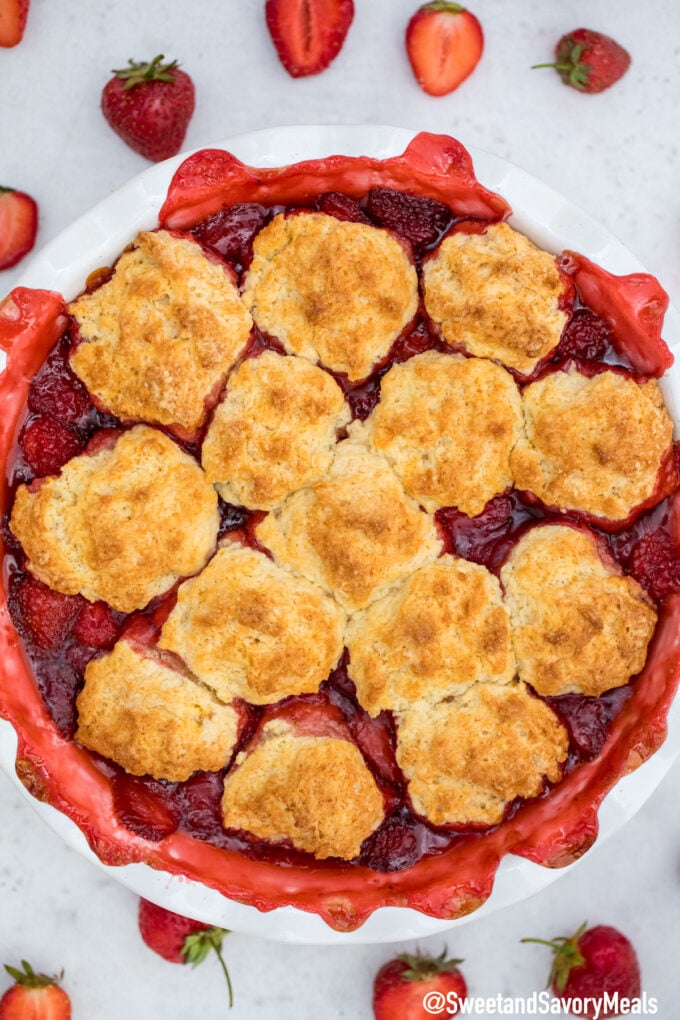 strawberry cobbler in a pie dish topped with golden brown biscuits