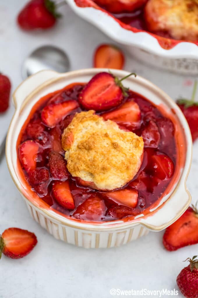 a bowl of a strawberry cobbler topped with a biscuit