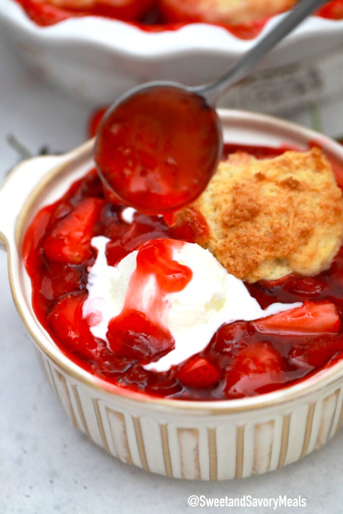 Photo of strawberry cobbler with ice cream and strawberry sauce.