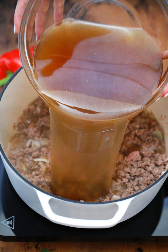 Adding broth to browned beef.