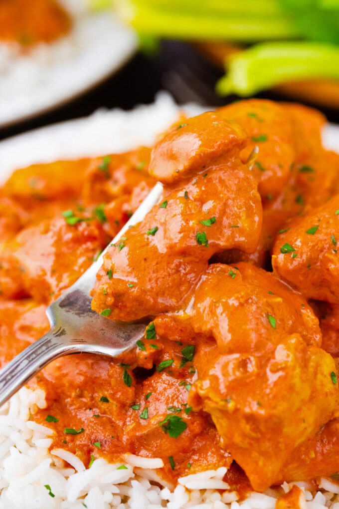 A forkful of creamy slow cooker tikka masala over white rice.