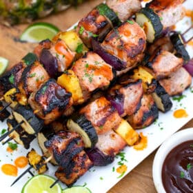 Grilled pork skewers on a white plate.