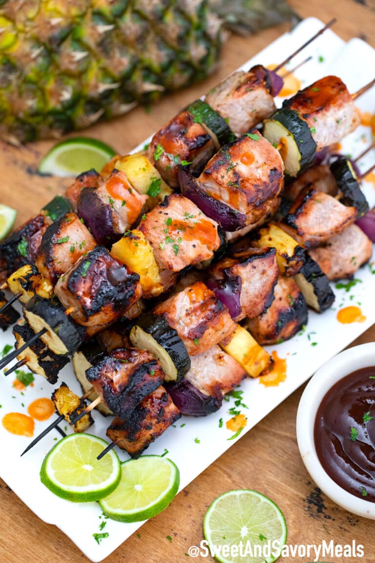 Grilled pork skewers on a white plate.