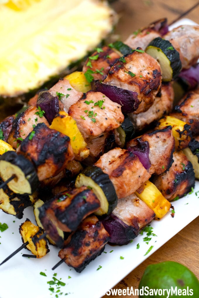 Grilled pork skewers on a white plate.