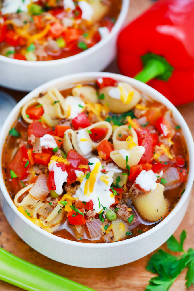 A bowl of beef and macaroni soup with vegetables.