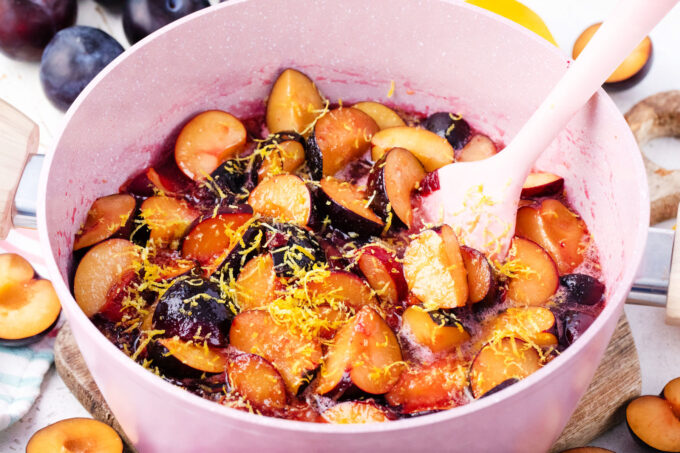 Mixing plums with lemon juice and lemon zest in a saucepan.