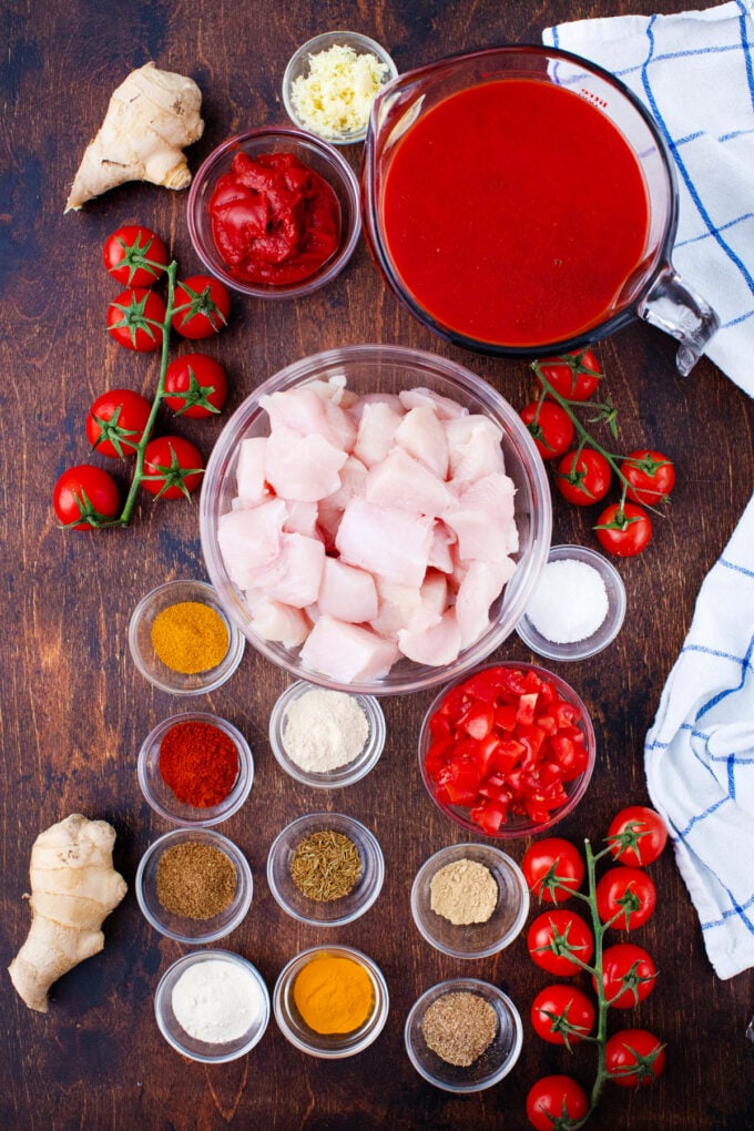 Overhead shot of slow cooker tikka masala ingredients in bowls on a wooden table.