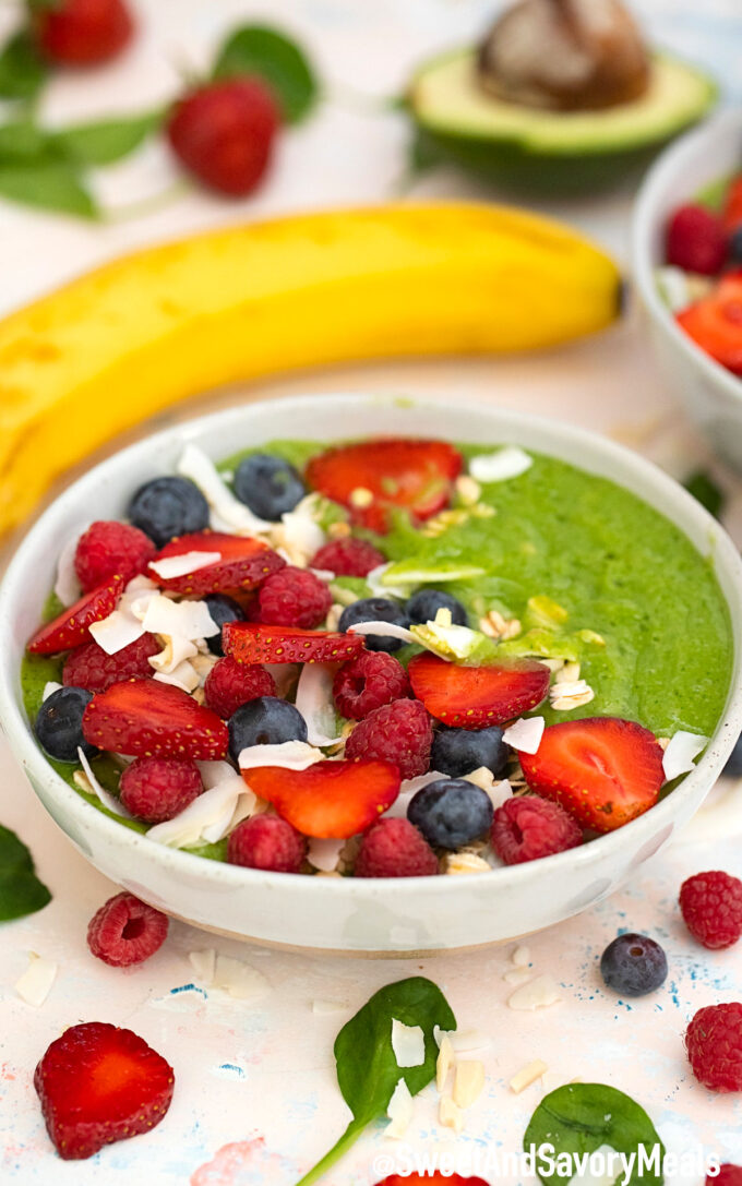 Green smoothie bowl with strawberries and blueberries.