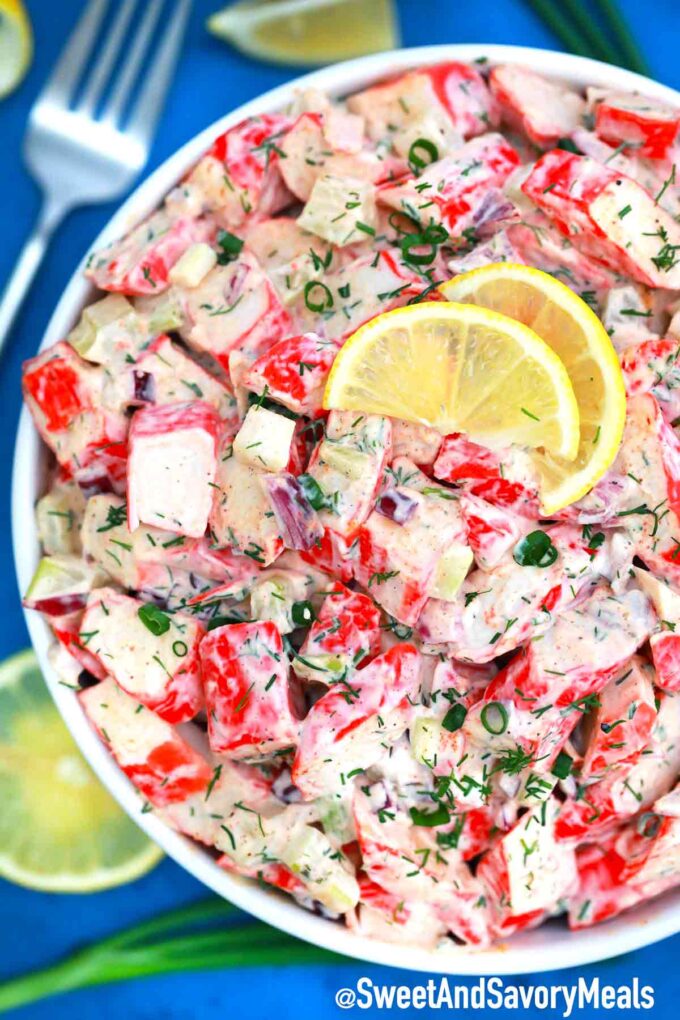 Crab salad with imitation crab and topped with sliced lemon in a bowl