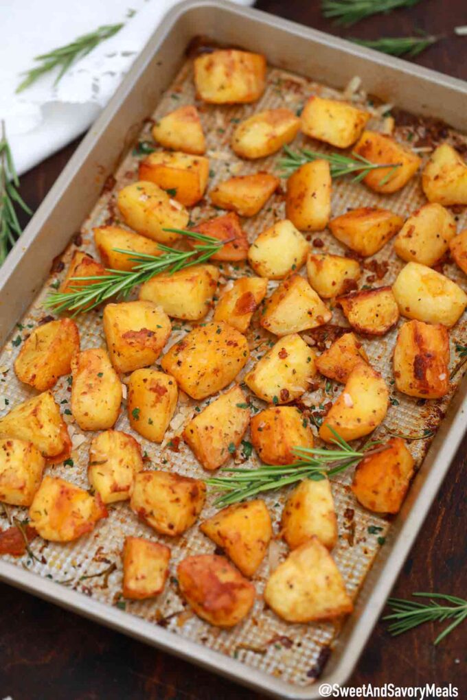 crispy garlic roasted potatoes on a baking sheet with fresh rosemary 