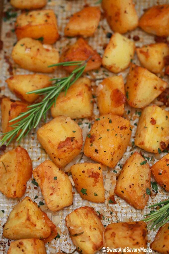 Close-up of roasted potatoes with rosemary and garlic on a baking sheet