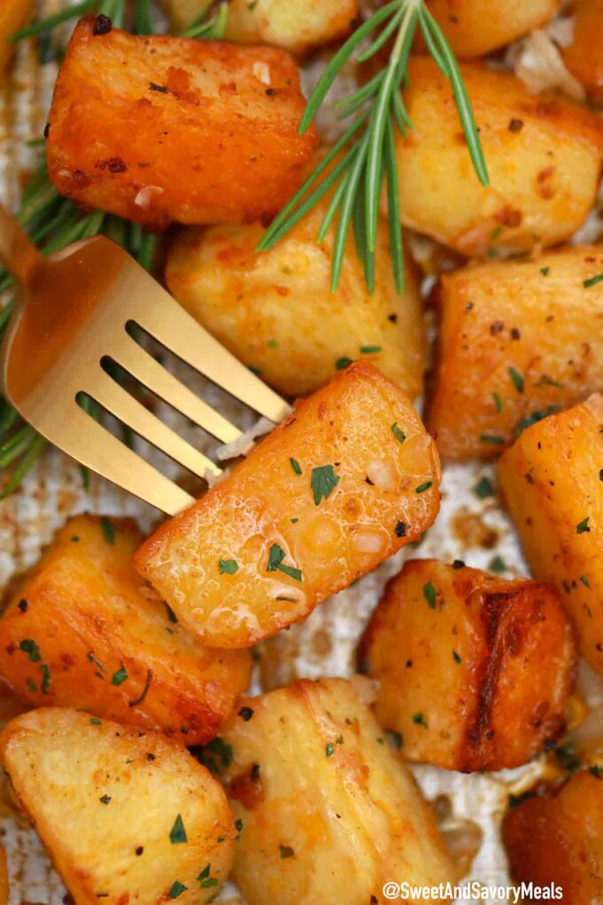 crispy and juicy garlic flavoured roasted potatoes on a fork