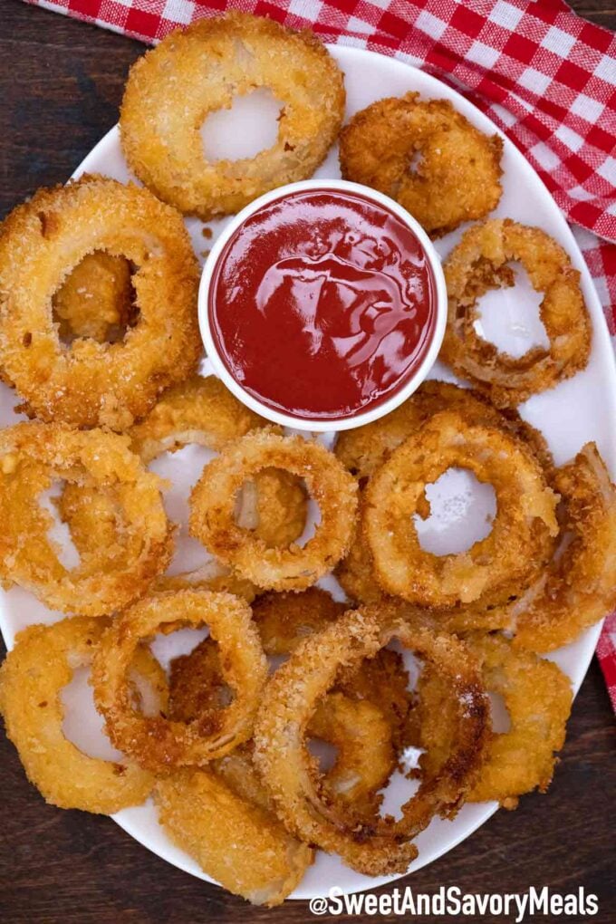 freshly served crispy onion rings on a plate with ketchup