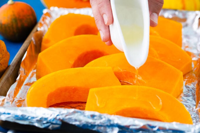 Drizzling pumpkin slices with coconut oil.