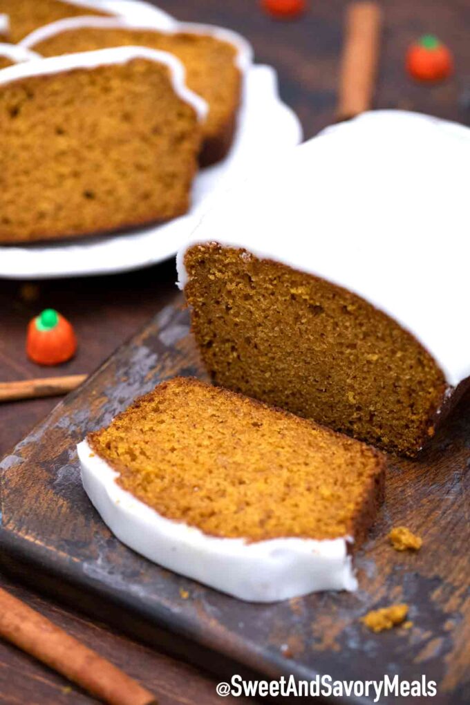 Sliced pumpkin bread with frosting on a wooden board