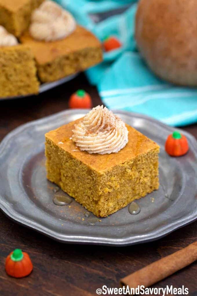 A slice of pumpkin cornbread topped with whipped cream on a silver plate