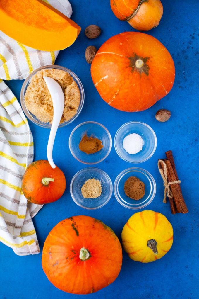 Overhead shot of pumpkin puree ingredients in bowls in a blue sruface.