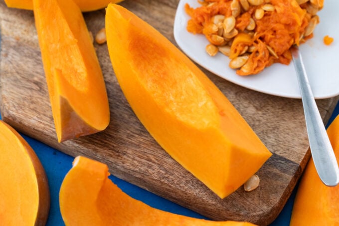 Scooping the seeds from a sliced sugar pumpkin.