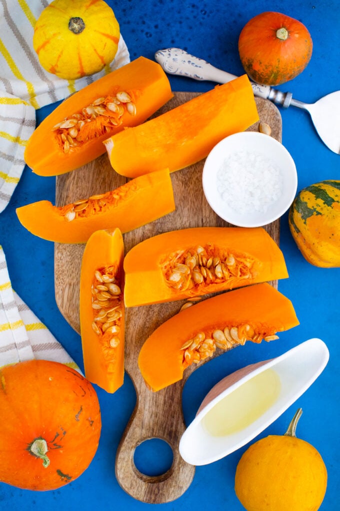 Overhead shot of roasted pumpkin ingredients arranged on a blue surface.