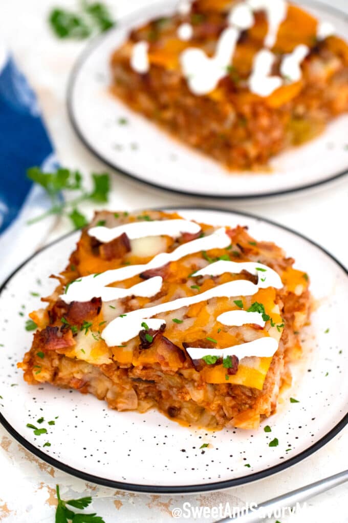 slice of stuffed cabbage casserole topped with sour cream on a white plate. 