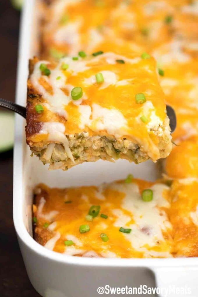 cheesy zucchini casserole topped with sliced green onions on a white baking dish