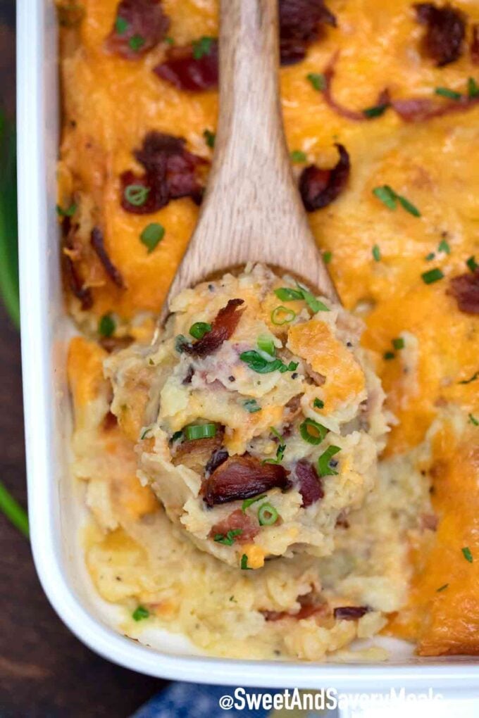 Baked potato casserole with bacon and cheese with a wooden spoon inside.