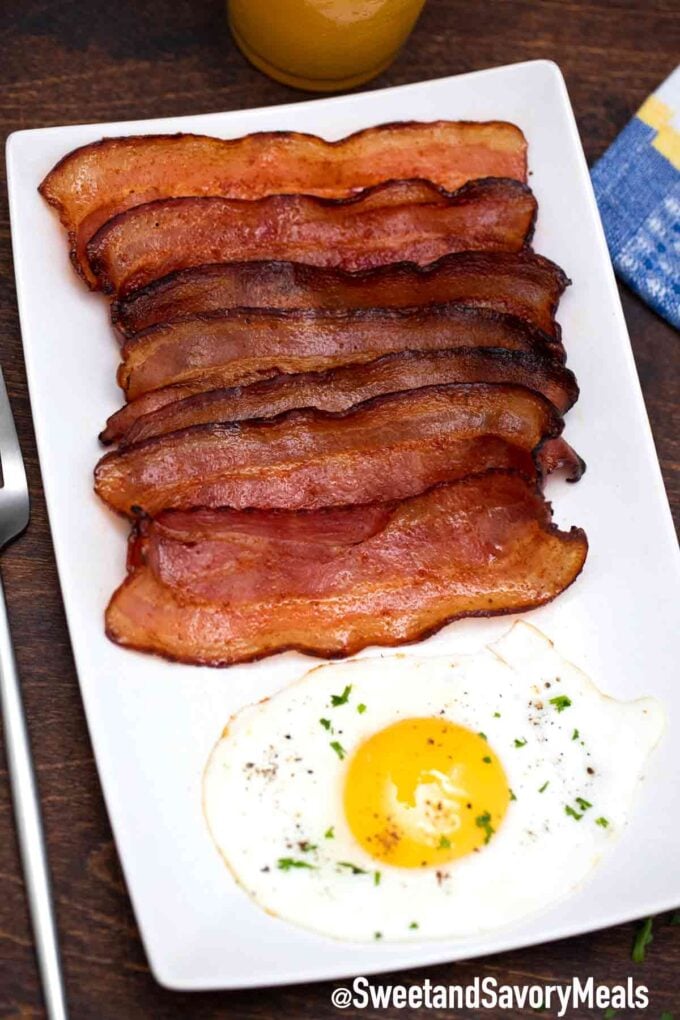 Fried bacon with an egg on a white plate