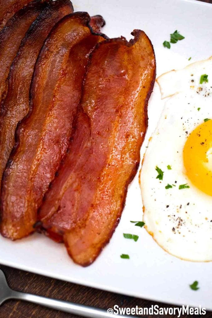 air fryer bacon on a plate next to a fried egg