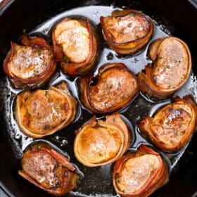 bacon wrapped pork medallions in a cast iron skillet